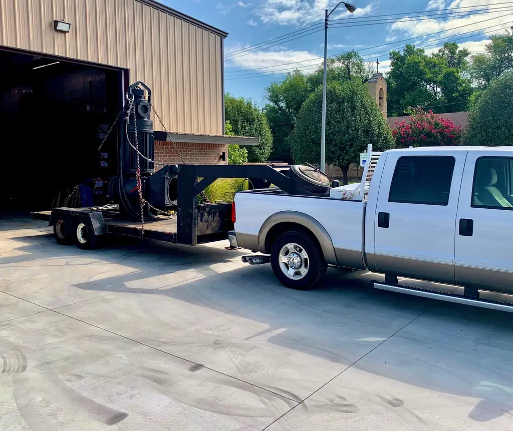 Our service truck and gooseneck trailer, loaded with a submersible pump for delivery.